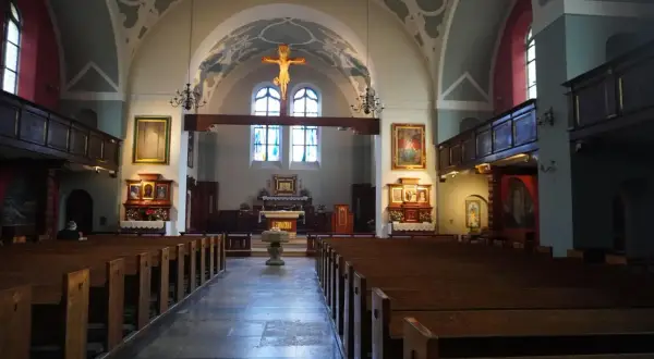 Wnętrze kościoła z ławkami, ołtarzem i krzyżem.